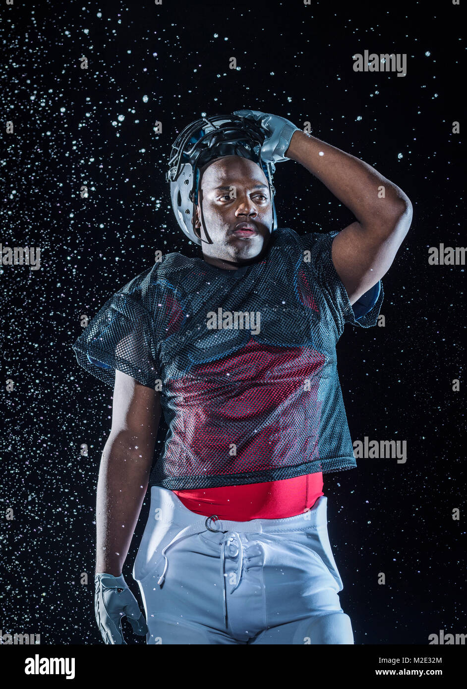 Water splashing on Black football player lifting helmet Stock Photo - Alamy