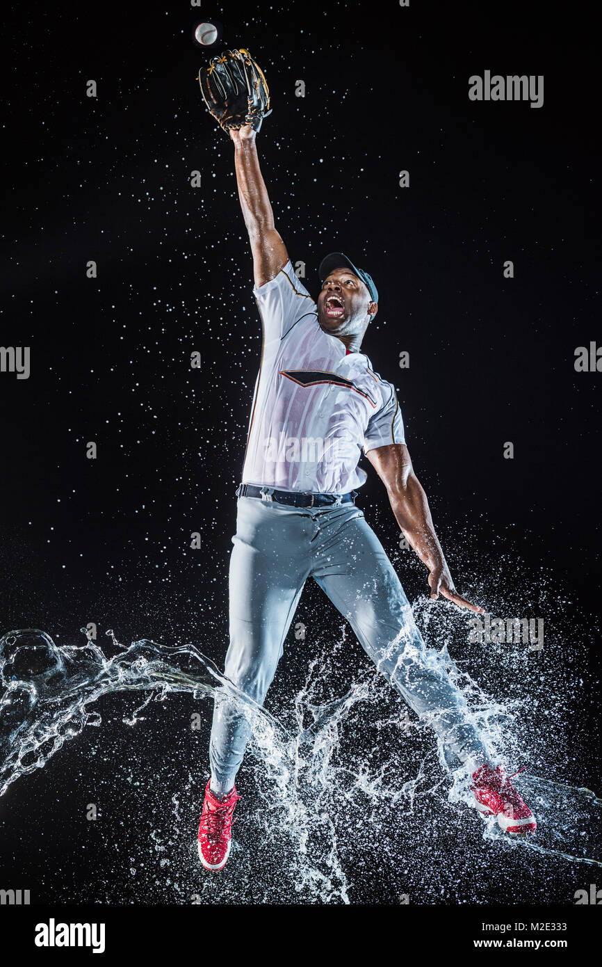 Water splashing on legs Black baseball player catching baseball Stock