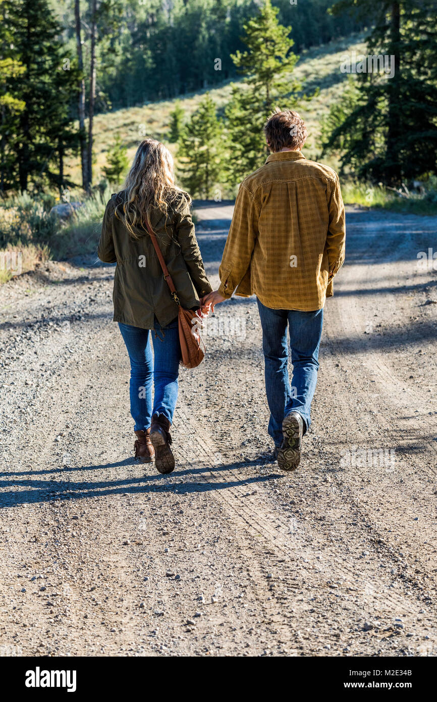 Caucasian couple walking on dirt road holding hands Stock Photo