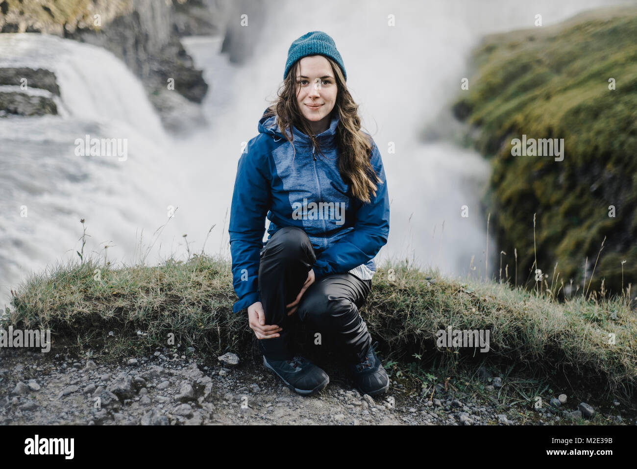 Portrait of smiling Caucasian woman sitting near waterfall Stock Photo