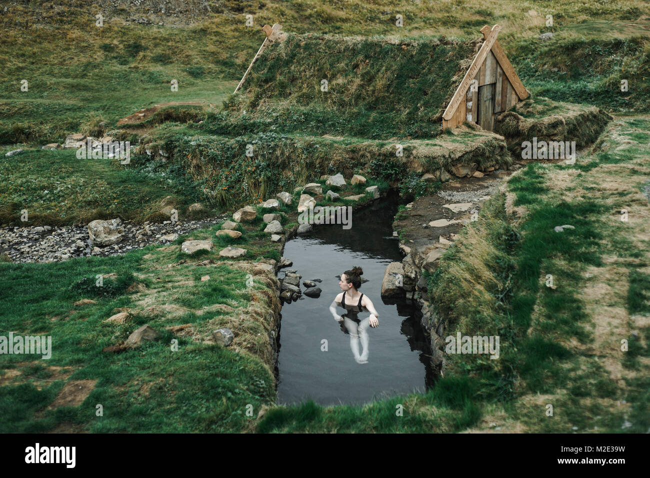 Caucasian woman swimming in pond near rural house Stock Photo