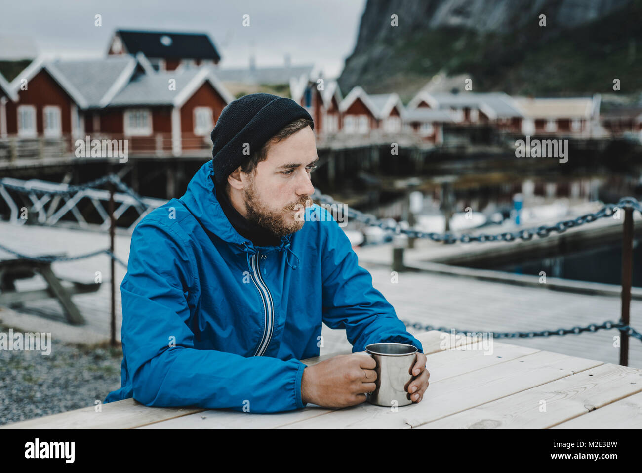 Pensive Caucasian man drinking coffee at table at waterfront Stock Photo