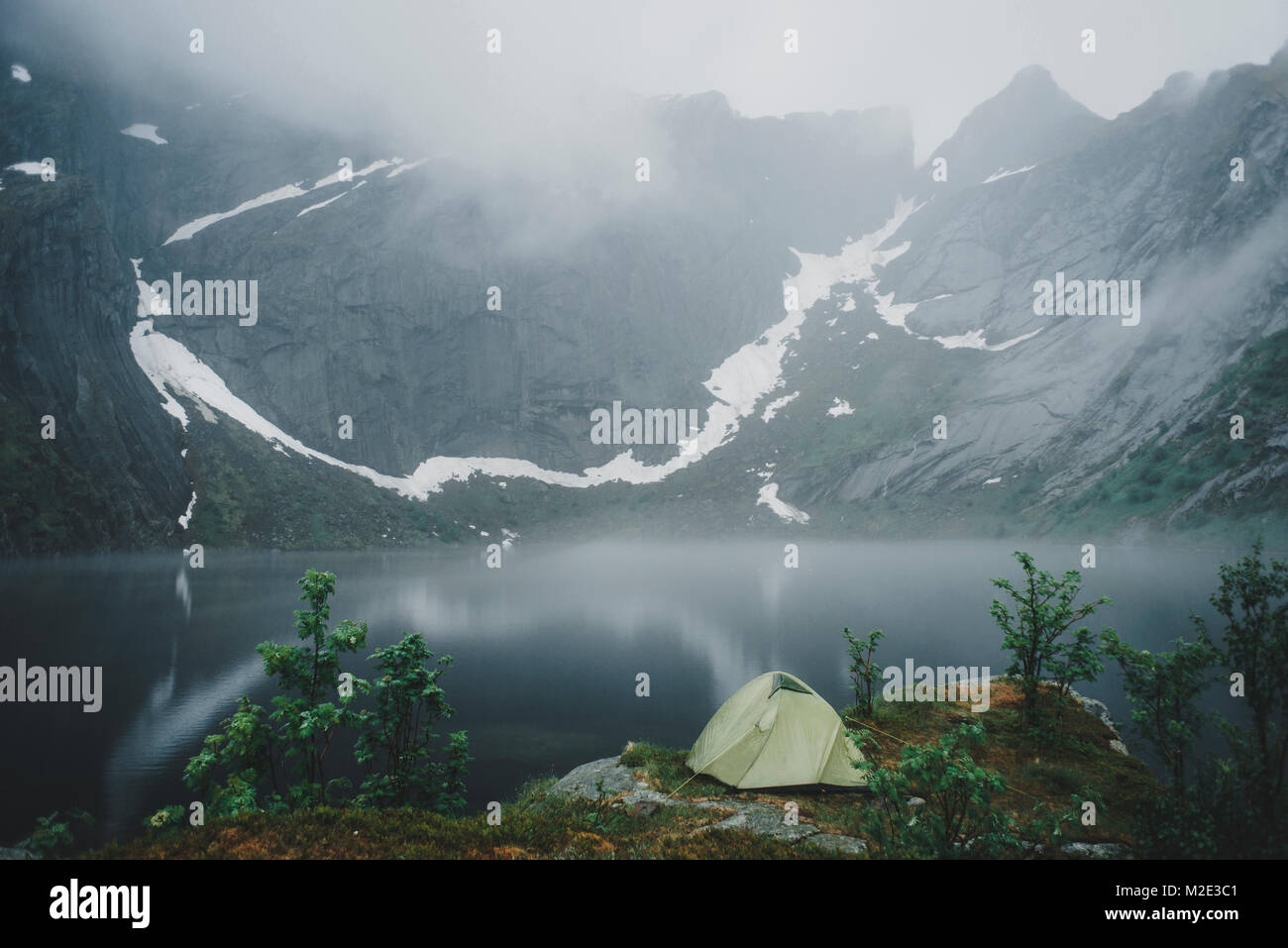 Camping tent near river in fog Stock Photo