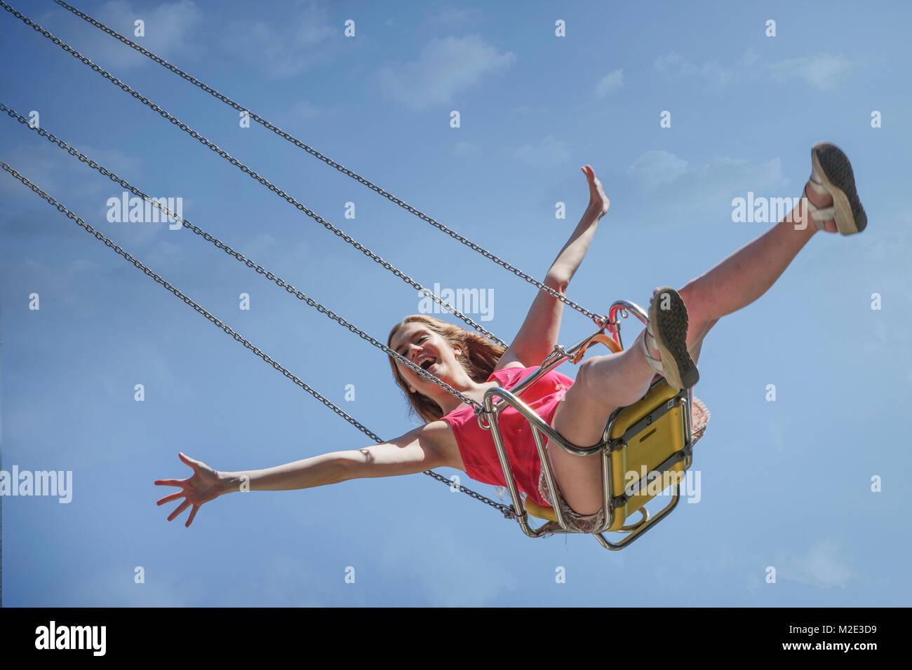 Smiling Caucasian woman riding swing on amusement park ride Stock Photo
