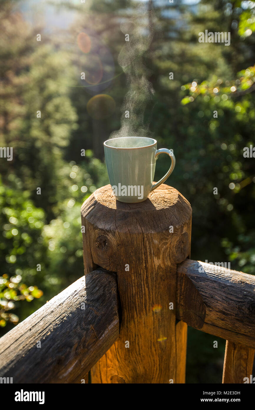 Steaming coffee cup on wooden post Stock Photo