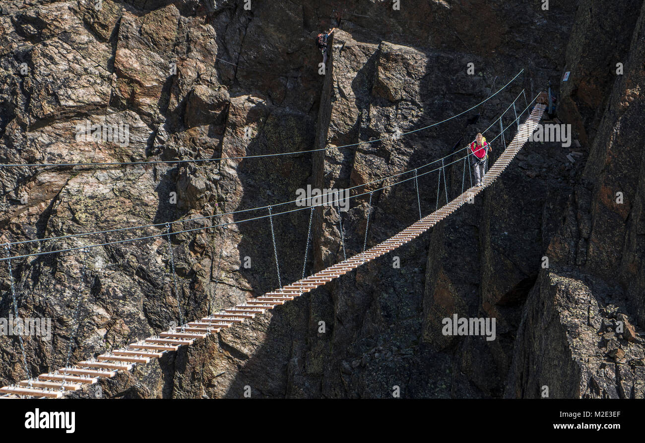 Caucasian man crossing rope bridge on mountain Stock Photo