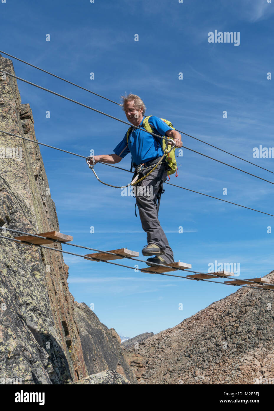 Caucasian man crossing rope bridge on mountain Stock Photo