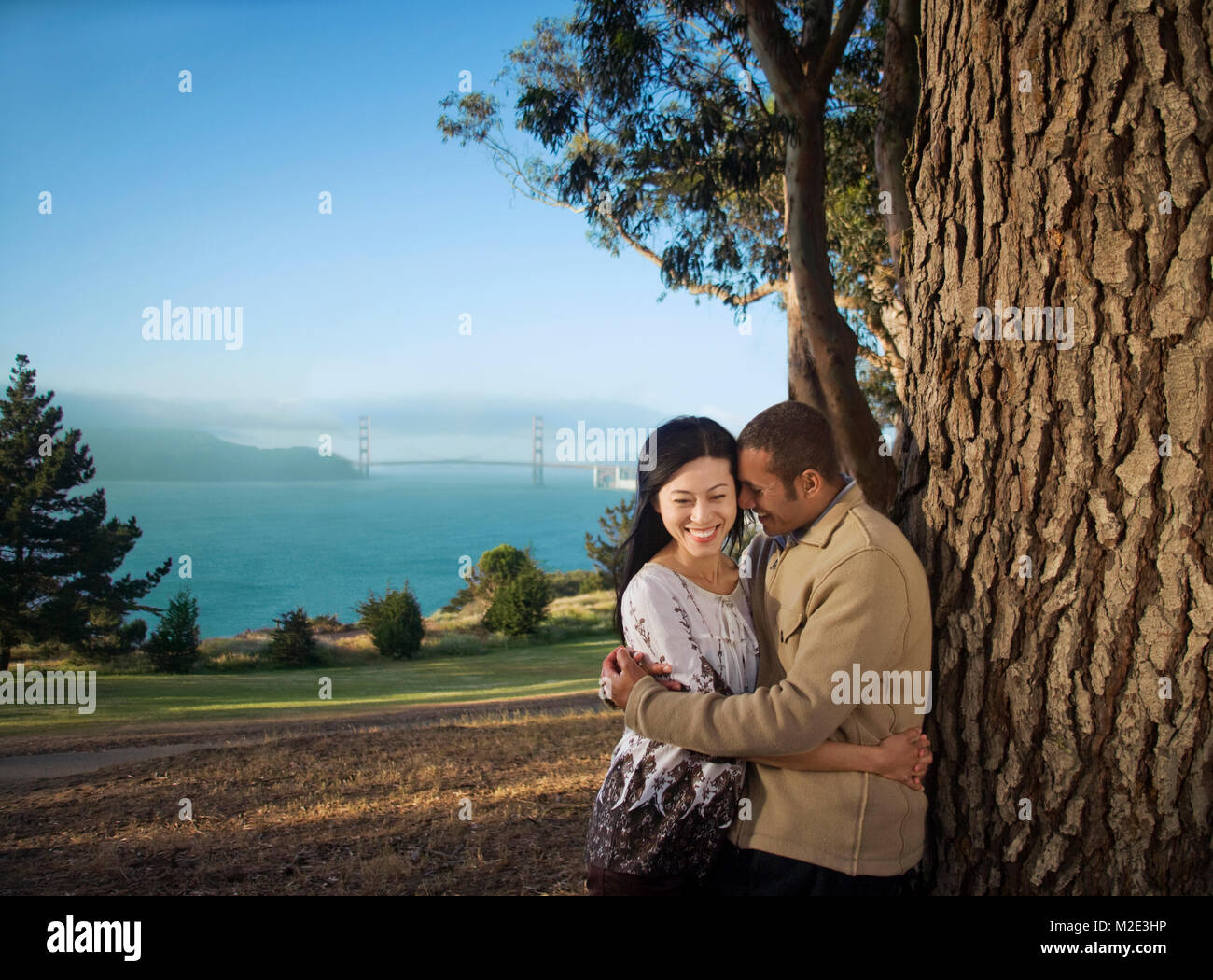 Couple hugging at tree near bay Stock Photo