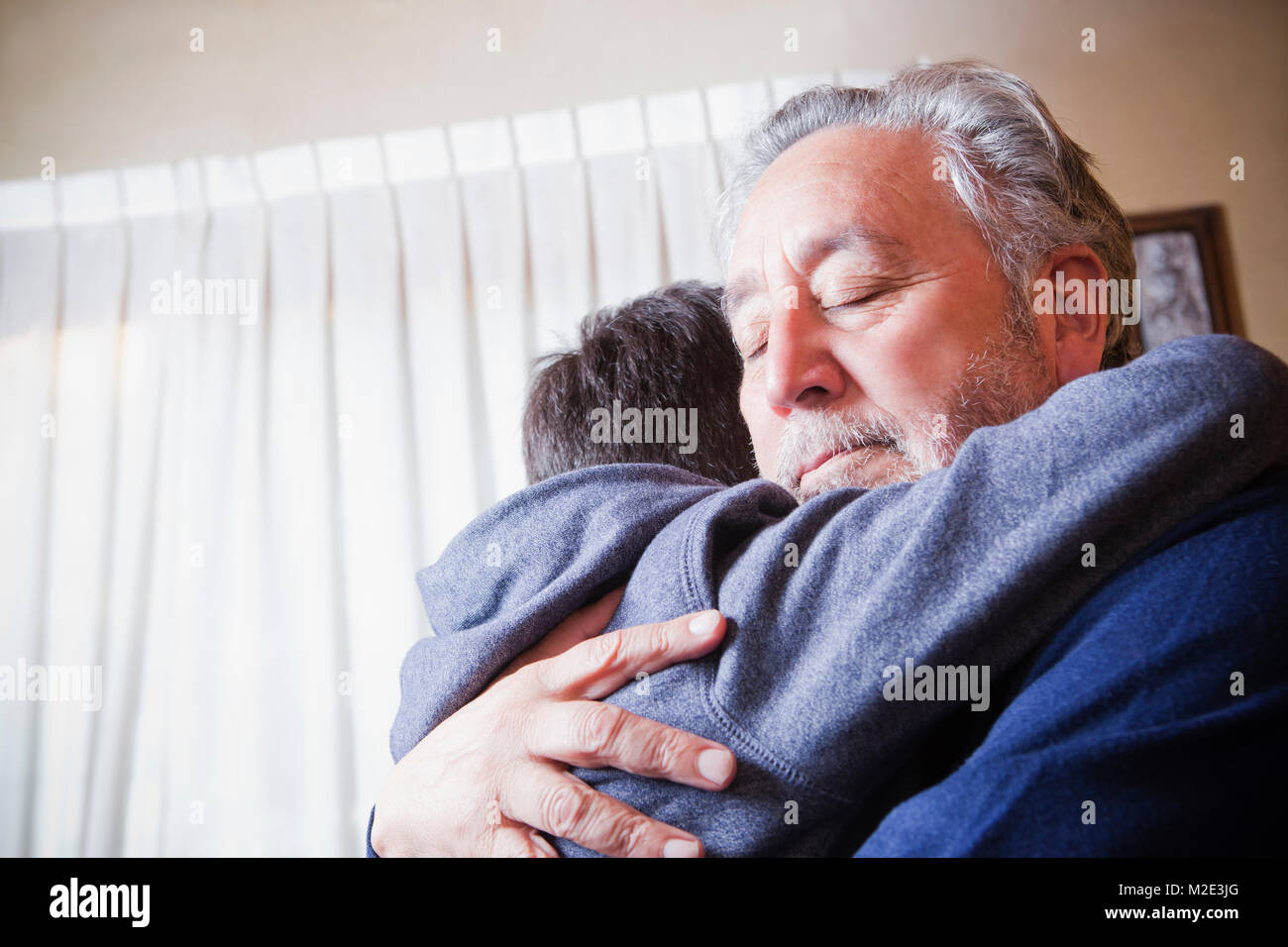 Hispanic grandfather hugging grandson Stock Photo