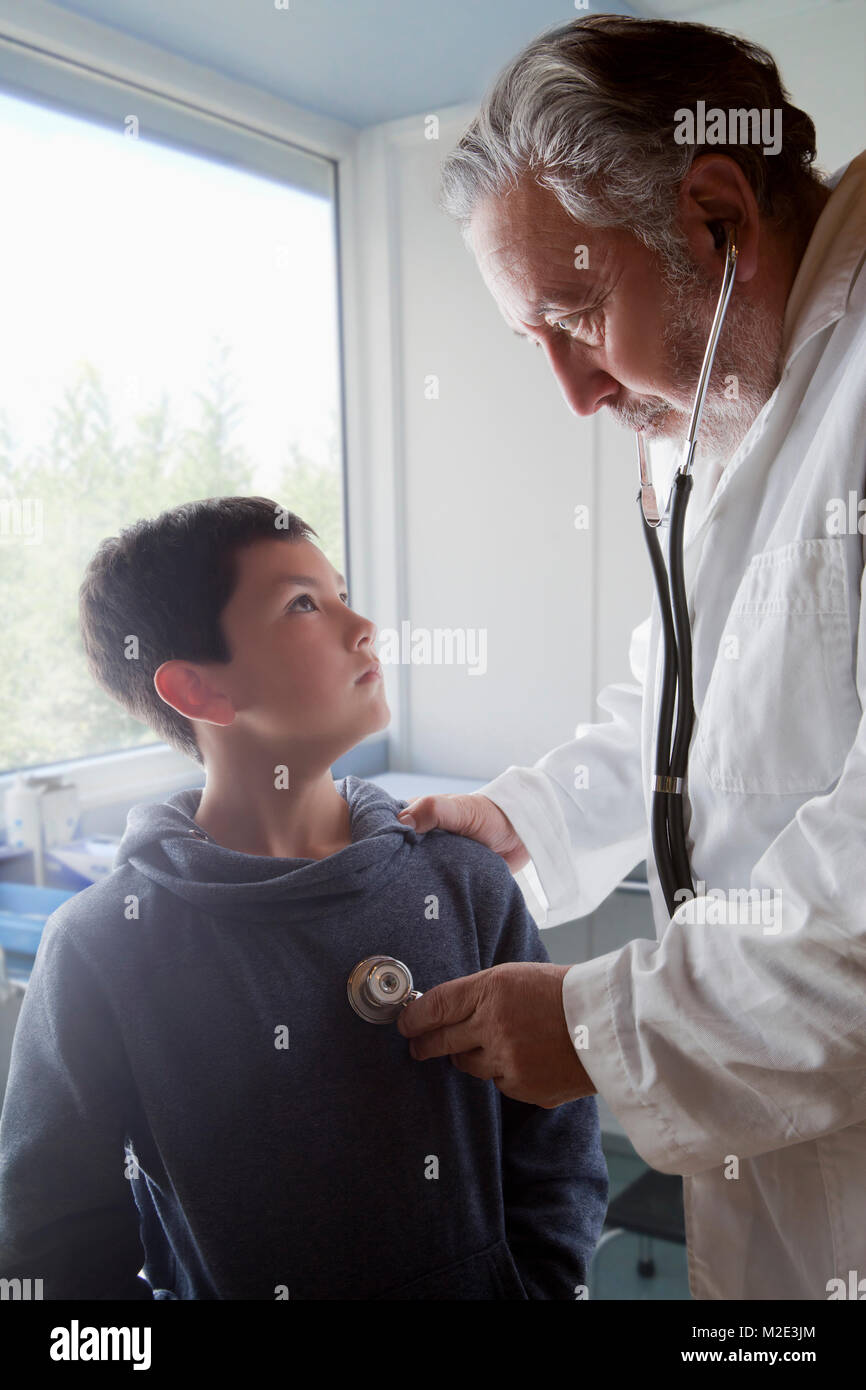 Hispanic doctor listening to chest of boy with stethoscope Stock Photo