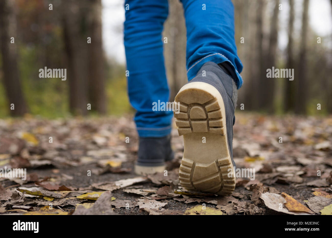 Sole of shoe of Caucasian boy walking on autumn leaves Stock Photo