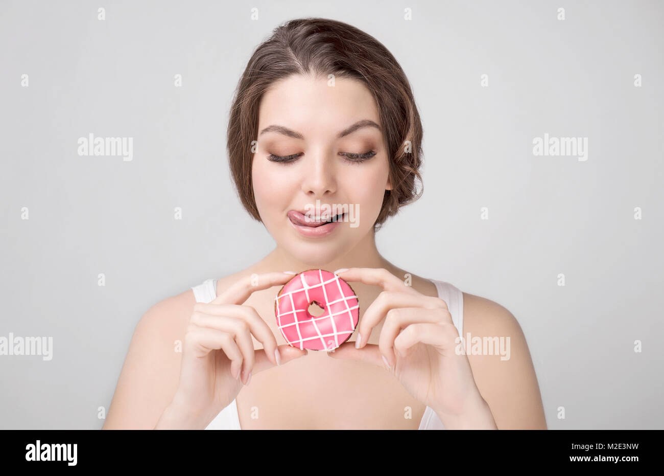Caucasian woman holding donut and licking lips Stock Photo
