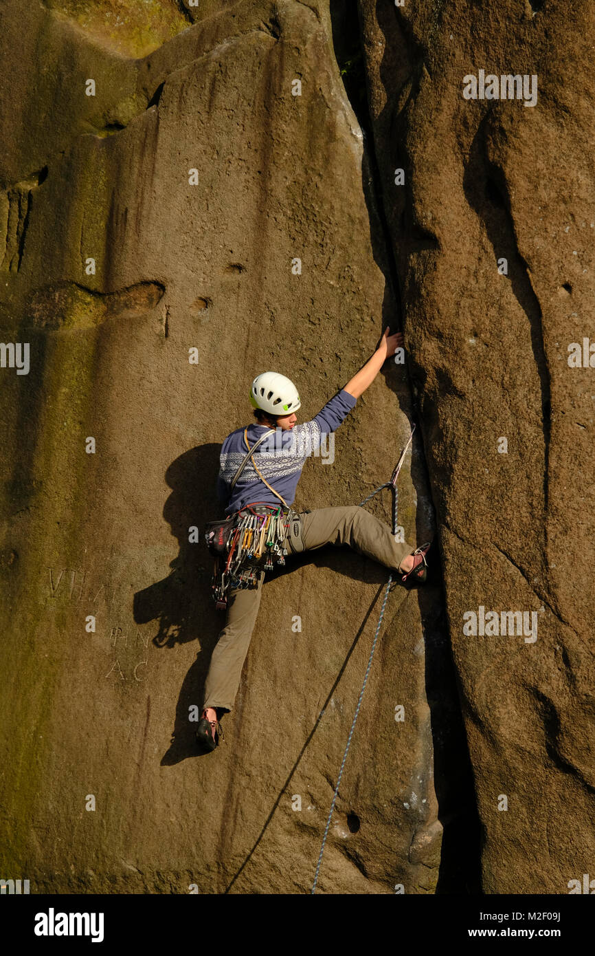 A rock climber at full stretch as he reaches for the next hold. Stock Photo
