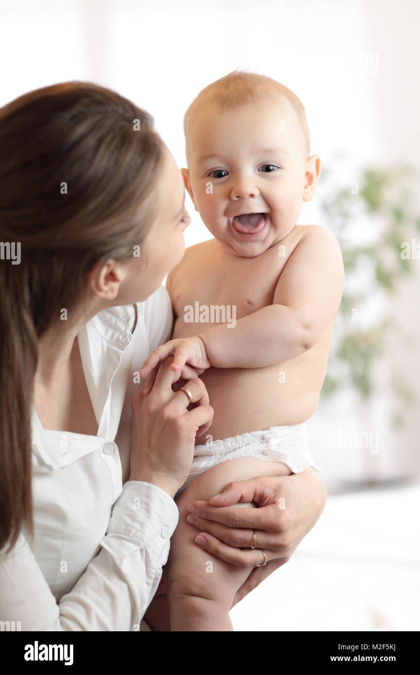 Happy family laughing faces, mom holding cute child baby boy. Young woman and her small son have a fun pastime. Stock Photo