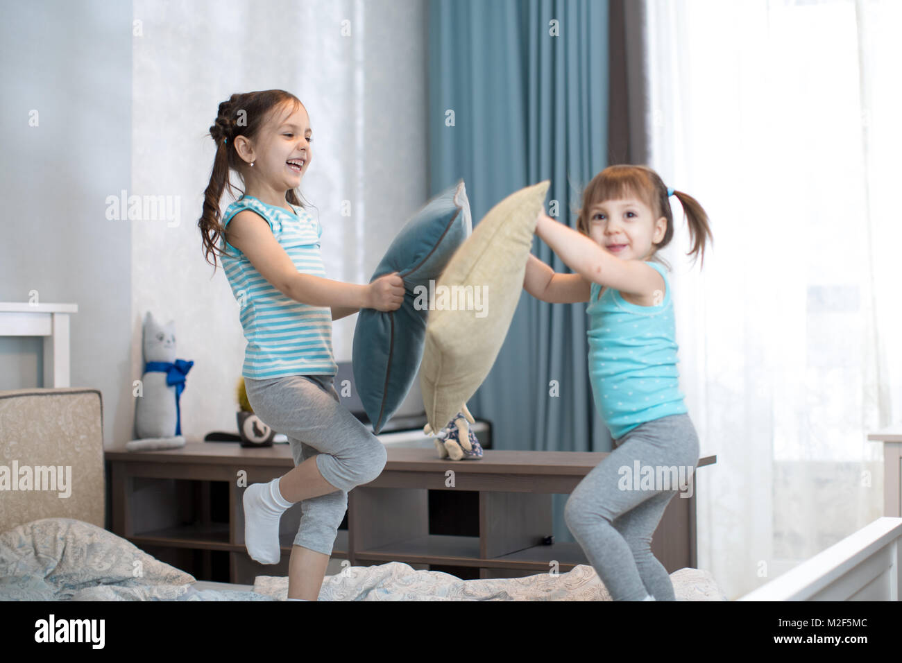 kids girls have fun playing with pillows in bedroom at home Stock Photo