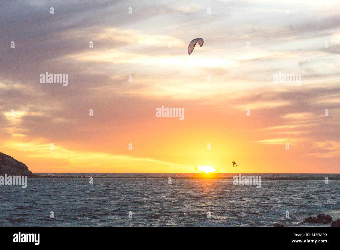 San Carlos, Sonora State, Mexico, February 7, 2018; at sunset on a chilly evening parasurfer rises gracefully above the cold blue Sea of Cortez while turning into the wind & is silhouetted briefly against the sun falling below the horizon before drifting down to the surface of the water & doing it again Credit: Dorothy Alexander/Alamy Live News Stock Photo