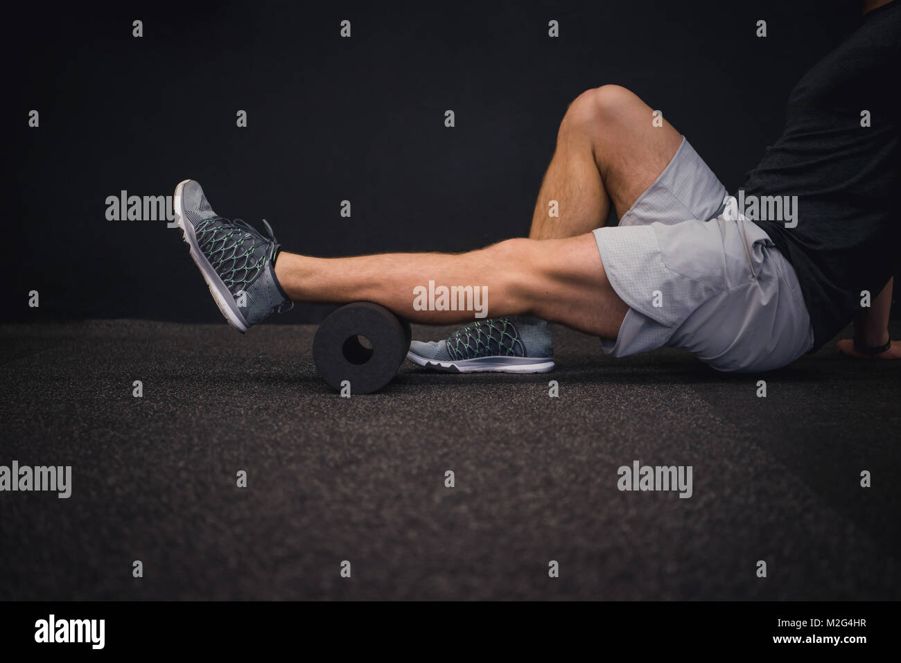 Athletic man using a foam roller to relieve sore muscles after a