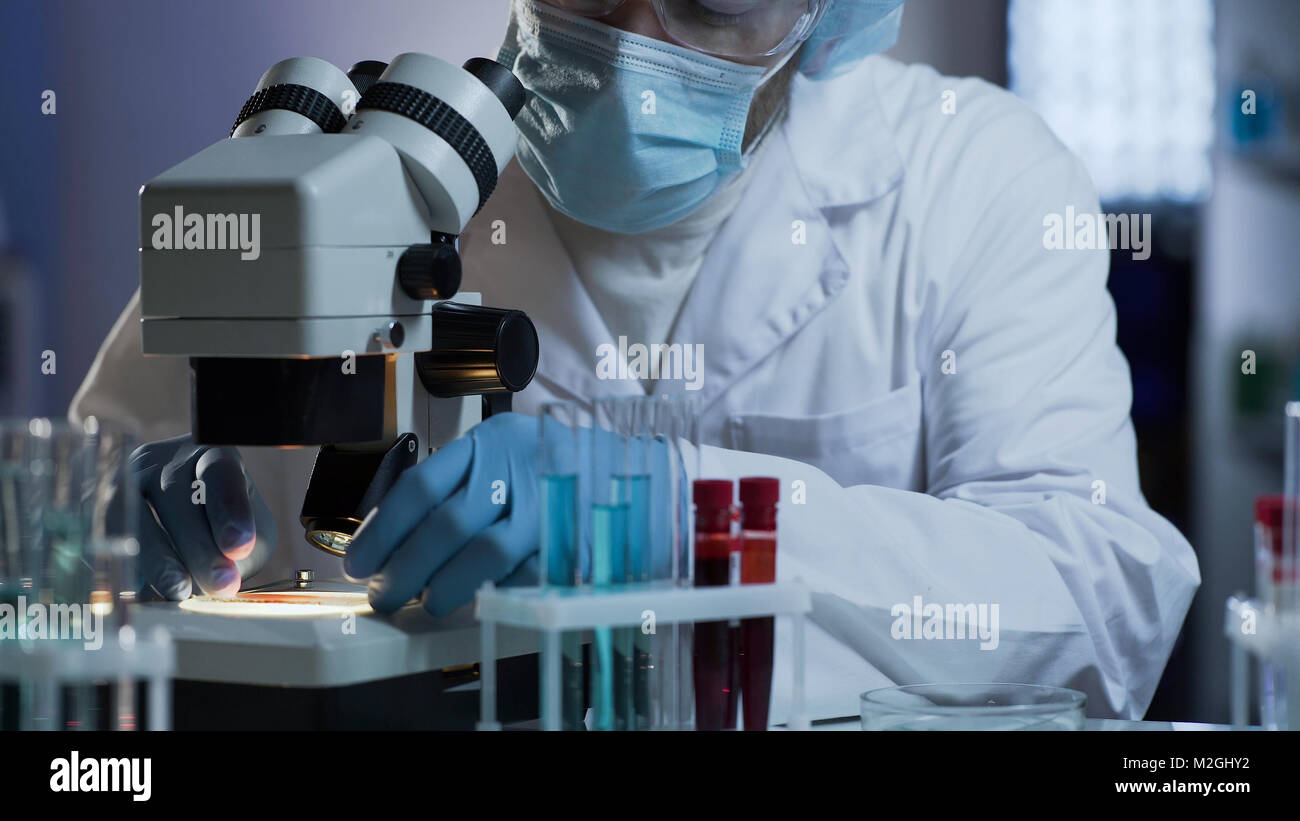 Medical scientist putting glass with biological material on microscope ...