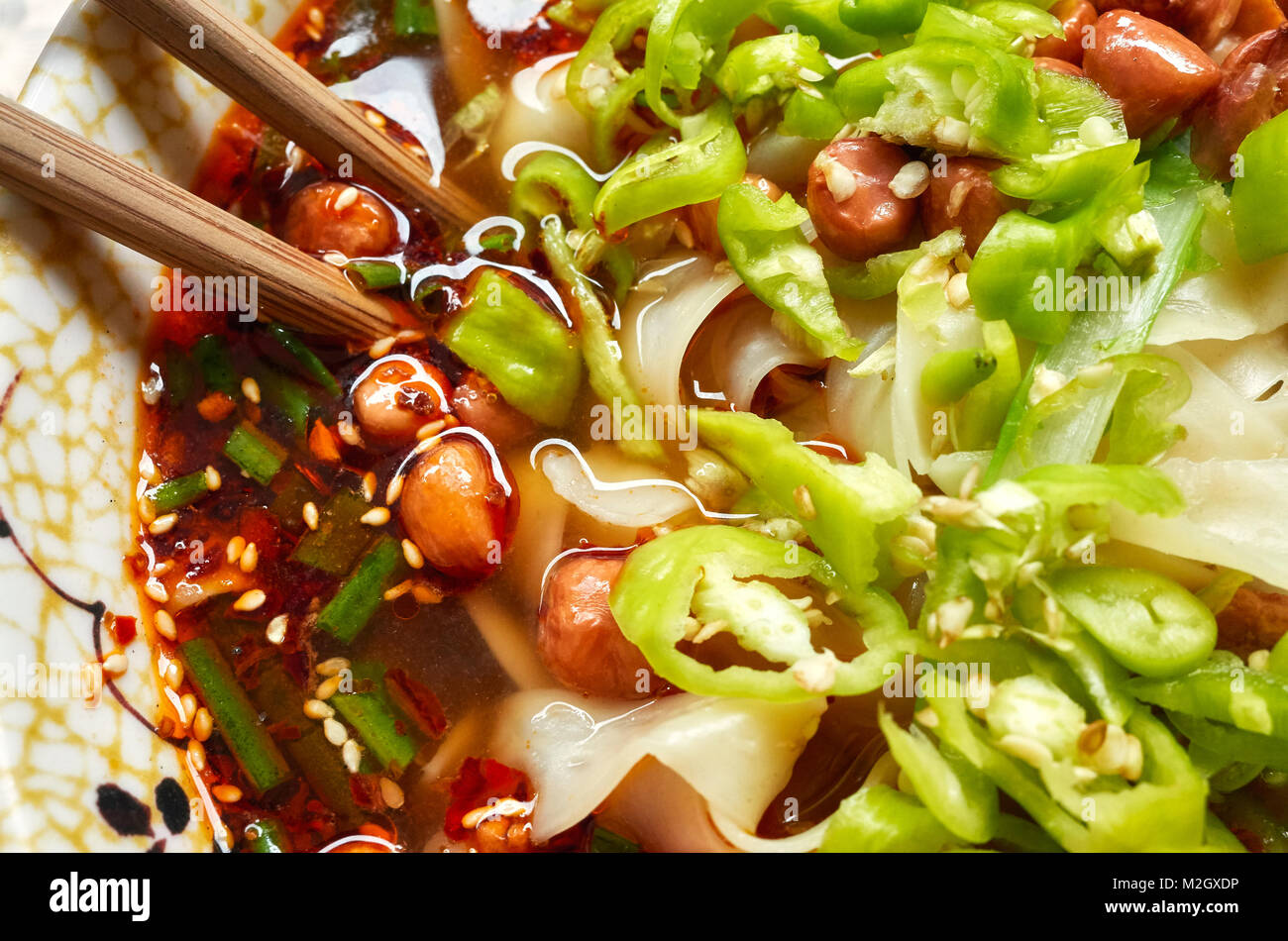 Spicy noodle soup with vegetables, herbs, peanuts and coriander, popular in Yunnan Province, shallow depth of field, China. Stock Photo