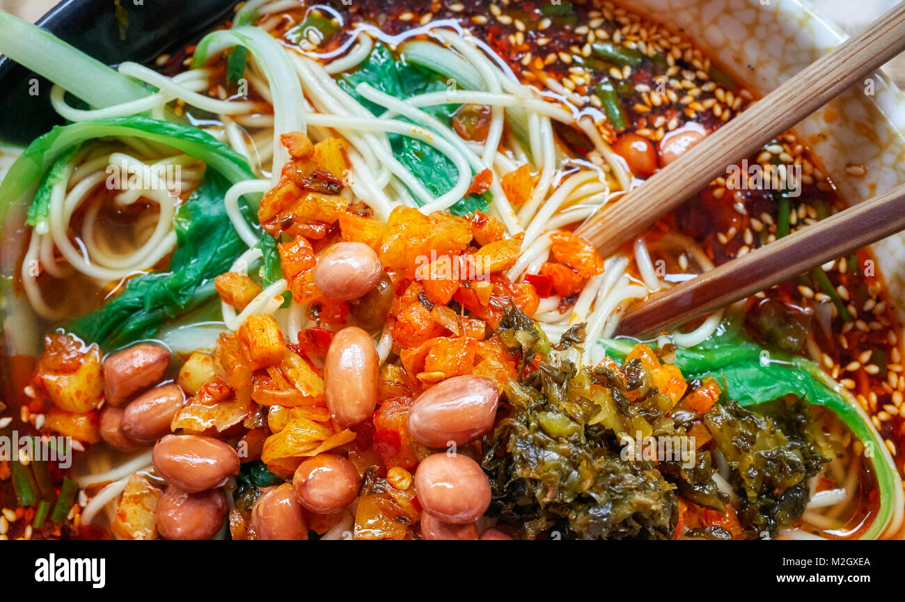 Spicy noodle soup with vegetables, herbs, peanuts and coriander, popular in Yunnan Province, shallow depth of field, China. Stock Photo