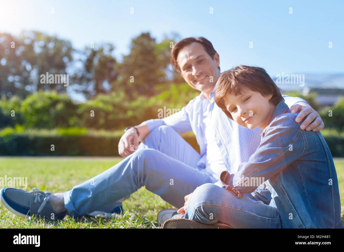 Harmonious father and son relaxing on grass together Stock Photo - Alamy