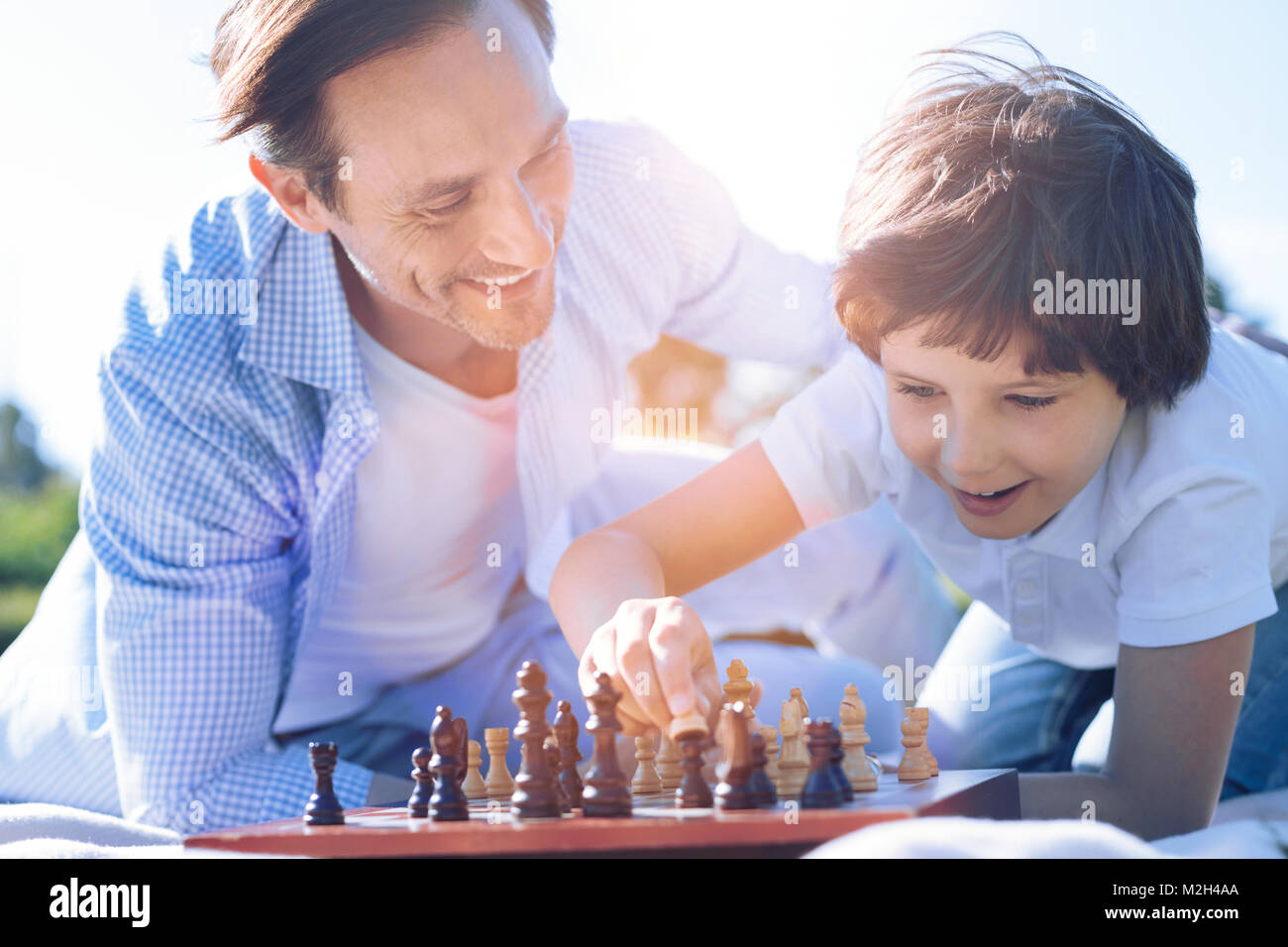 Proud father watching son playing chess Stock Photo