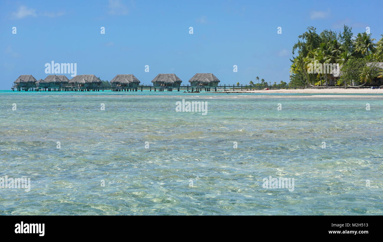 Tropical island with bungalows over water in the lagoon, Tikehau atoll, Tuamotus, French Polynesia, Pacific ocean, Oceania Stock Photo