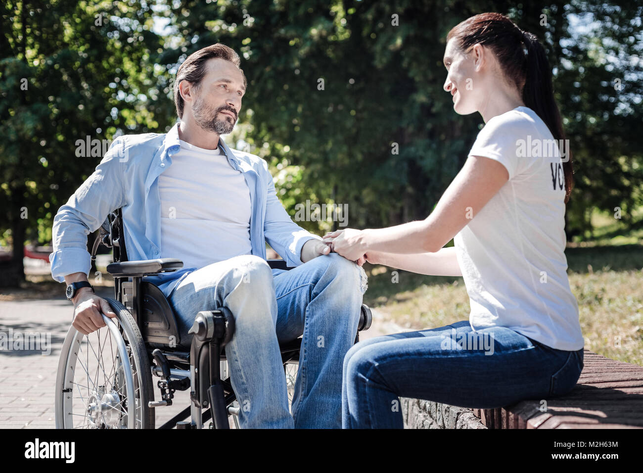 Positive nice woman looking at the disabled man Stock Photo