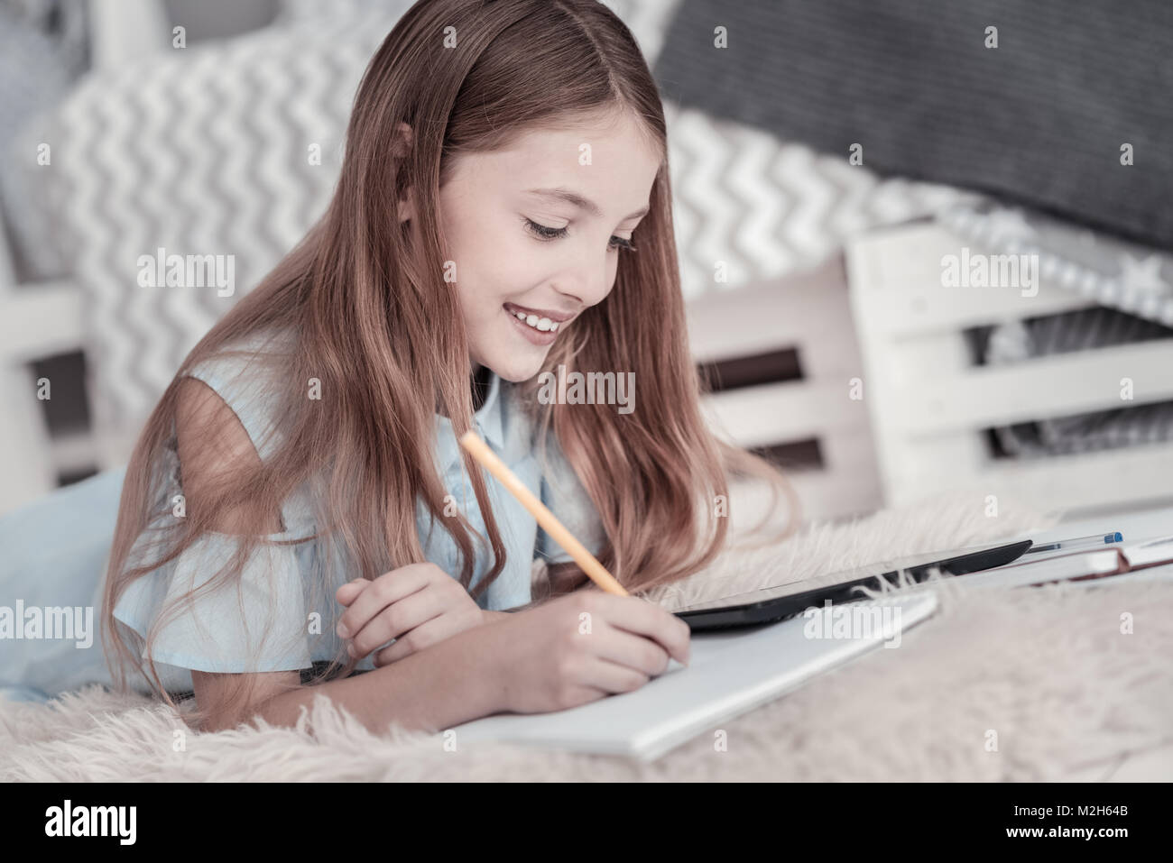 Happy girl drawing while lying on the floor Stock Photo - Alamy