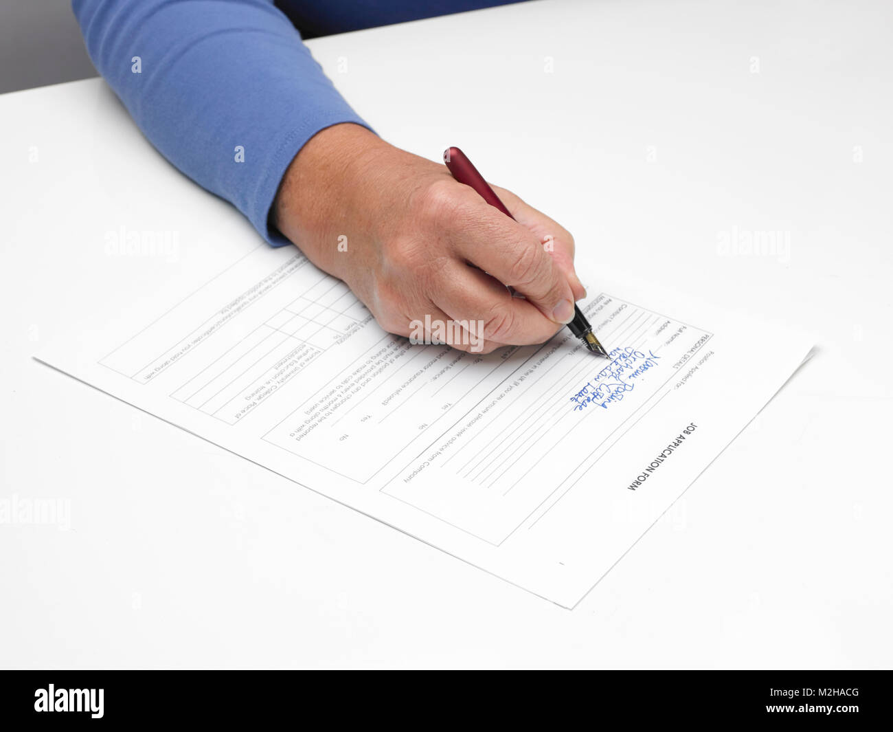 a female hand filling in a job application form with pen Stock Photo