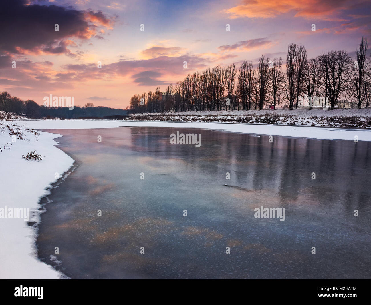 beautiful sunset on the frozen river. location Nealezhnosti embankment in Uzhgorod. beginning of the longest European linden alley in winter Stock Photo