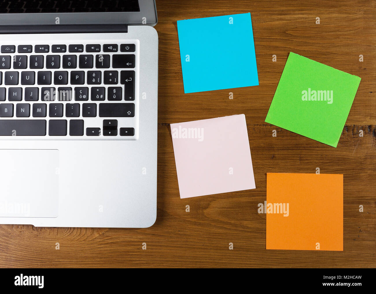 Colored blank post-it with office supplies on wooden table. Top view with post-it for copy space Stock Photo