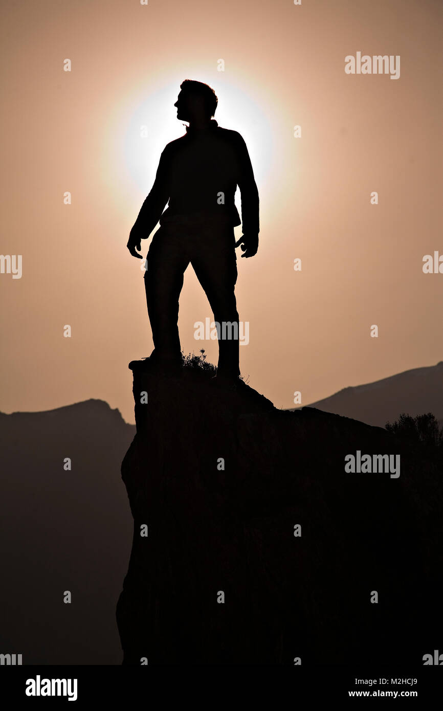 Silhouette of man on peak of mountain crag Stock Photo