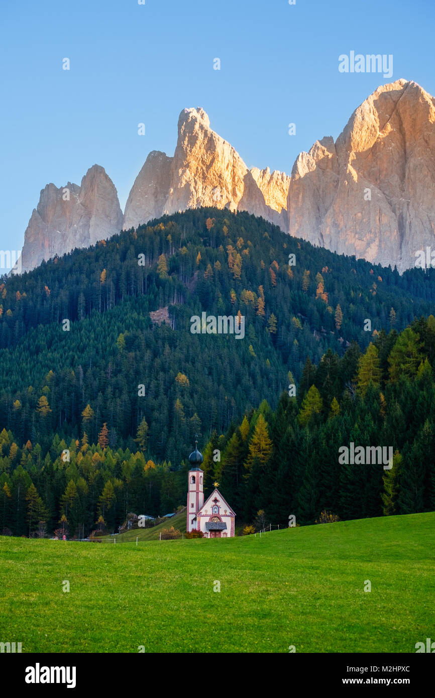 Beautiful autumn forest with baroque Church of St. Johann in Val Di Funes, Dolomites, Italy Stock Photo