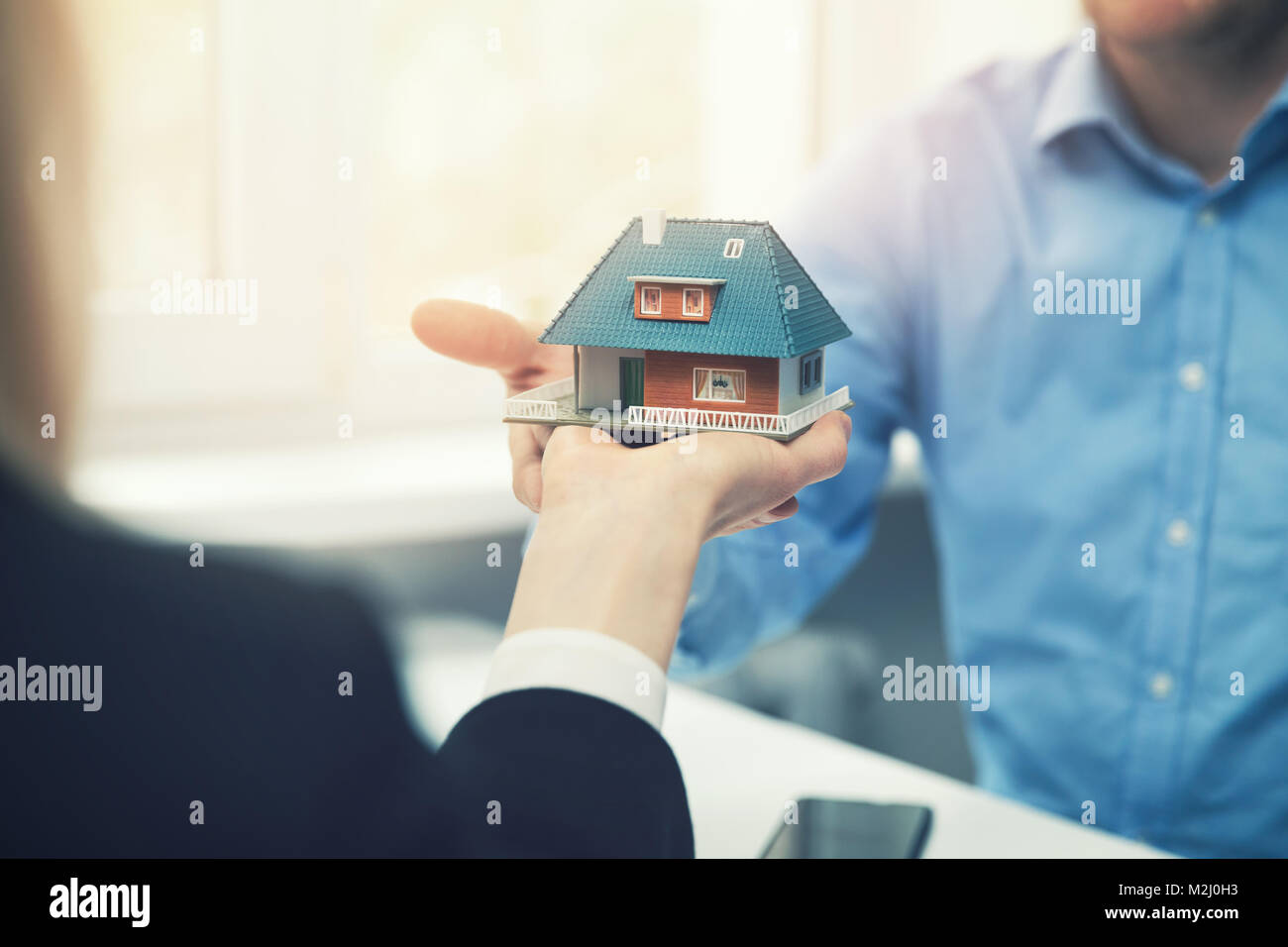 real estate agent or architect presenting house model to customer Stock Photo