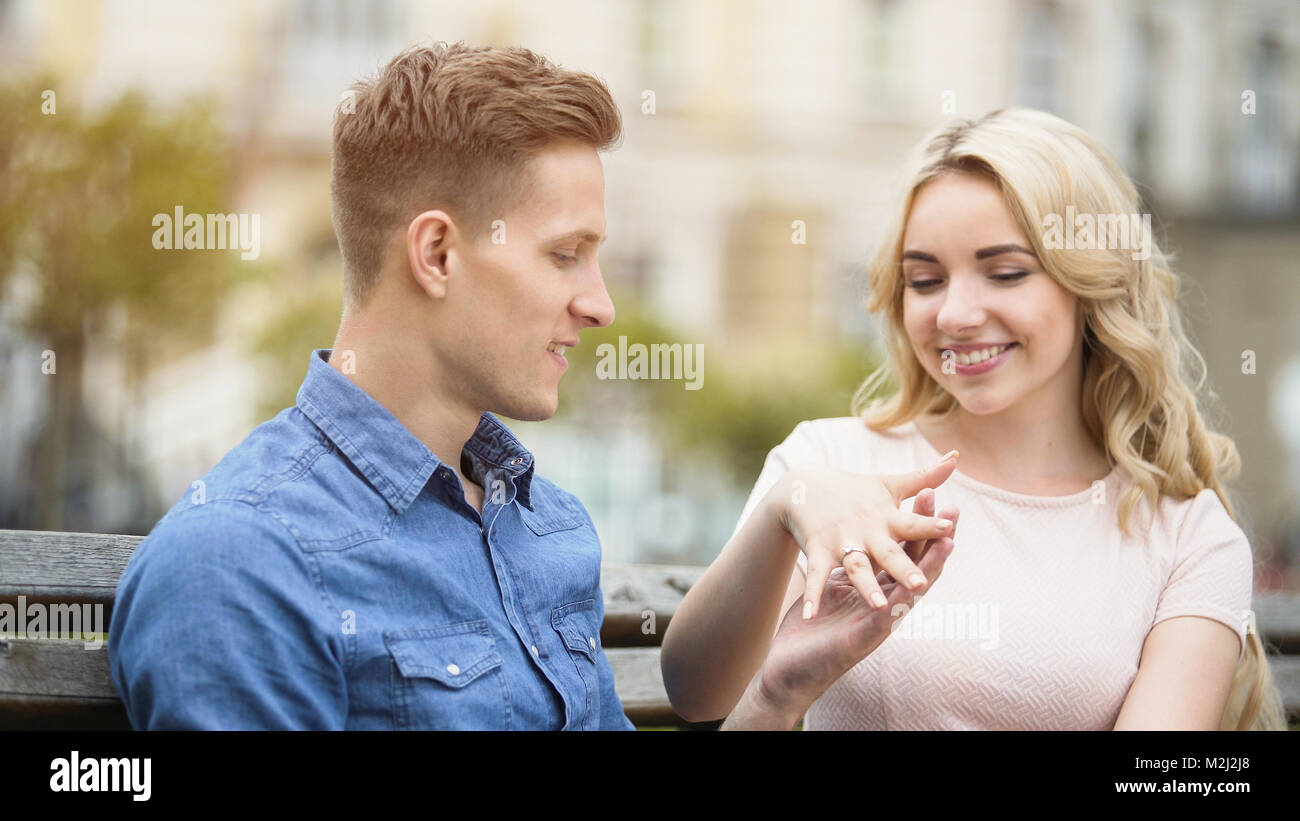 Excited young woman showing engagement ring on finger to beloved