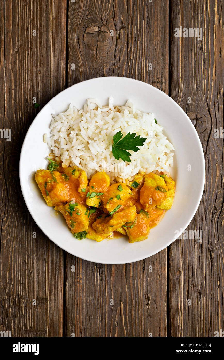Hot spicy chicken curry with rice on wooden table. Top view, flat lay Stock Photo