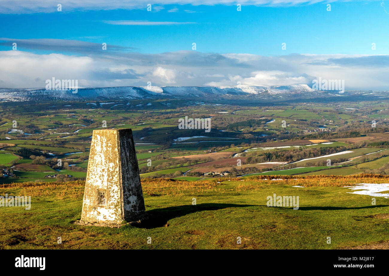 The trig point (triangulation pillar) on Garway Hill, Herefordshire, looking towards the Black Mountains in the Brecon Beacons national park, Wales Stock Photo