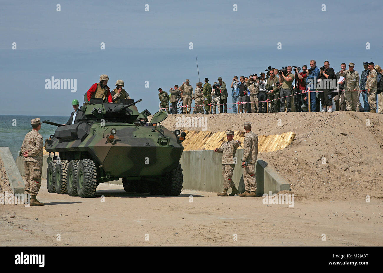 Latvian President Valdis Zatlers (in red on top of vehicle) rides a Light Armored Reconnaissance Vehicle through the beach entry access point constructed to aid maritime preposition force offload exercises and increase access to local recreation areas here. President Zatlers visited the Marines and Sailors of 4th Landing Support Battalion and Naval Beach Group 2, who have been working together with Latvian forces to conduct maritime preposition force offload operations and other training events here since the start of the exercise June 6. Latvian president rides in Marine Corps vehicle by EUCO Stock Photo
