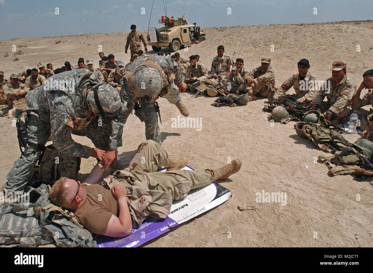 060427-N-8252B-087 Musayyib, Iraqi (April 27, 2006) - Sgt Daniel Gunn and Spc Kevin Smith prepare to give Spc Brad Miller an IV during a medical course given to the Iraqi Army. Company B, 2nd Battalion, 8th Infantry Regiment, 2nd Brigade Combat Team, 4th Infantry Division gives an Iraqi Army division a two week training course in basic military training. (Official U.S. Navy Photo by Photographer's Mate 2nd Class Katrina Beeler)(Released) (Released by: Capt. Ryan Gavin (Information Officer) VOIP: 676-8067 Email: ryan.gavin@bct2id4.army.smil.mil) Desert training by United States Forces - Iraq (I Stock Photo