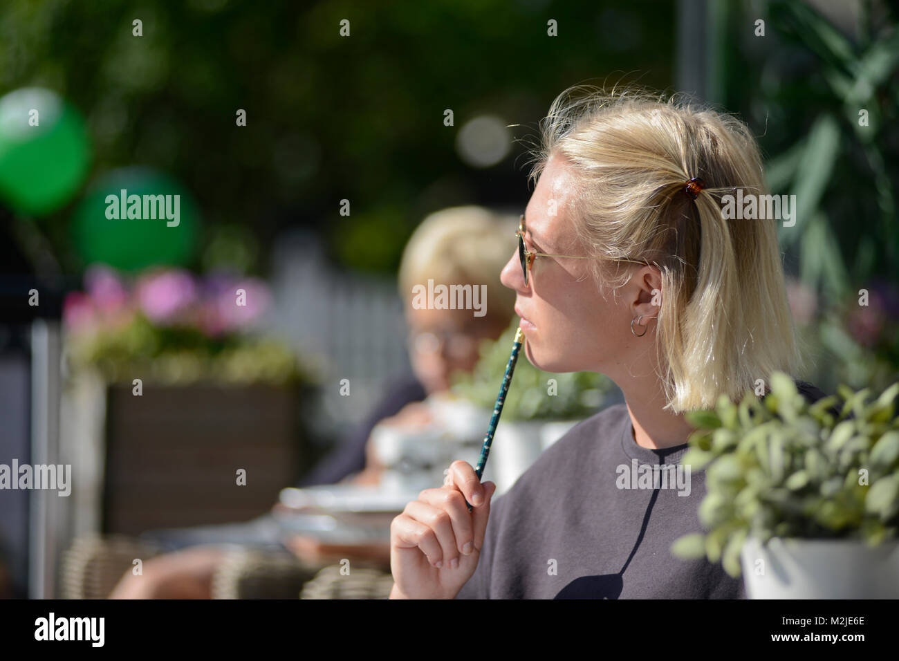A blonde student reading a book while having a morning coffee. Oslo, Norway Stock Photo