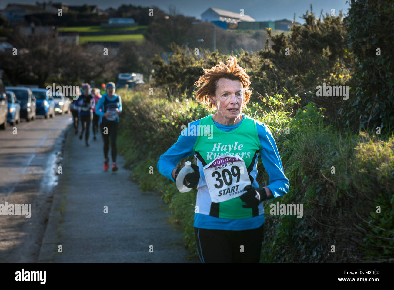 A mature female runner competing in a road race in Newquay Cornwall. Stock Photo