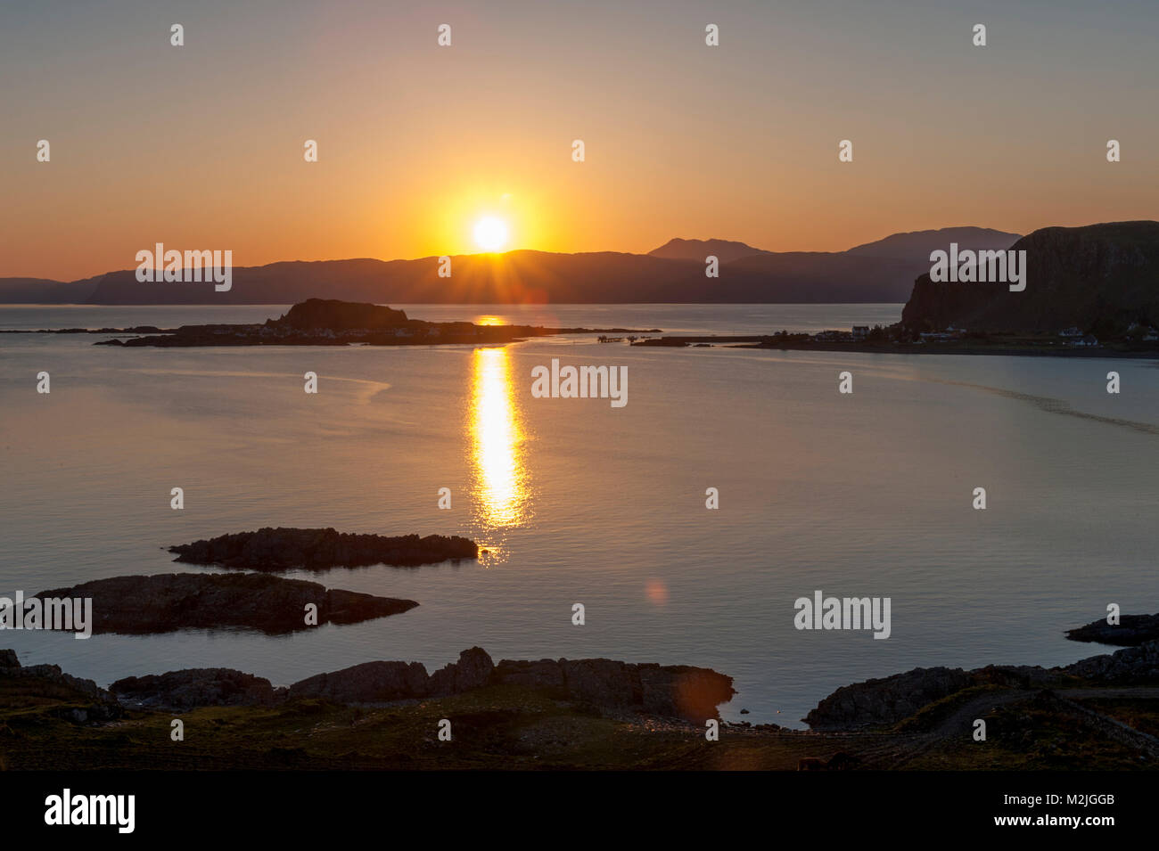 Stunning view of village of Easdale Island  Ellenabeich   Seil Island, Scotland, as the sun sets behind Isle of Mull accross the water  Stock Photo