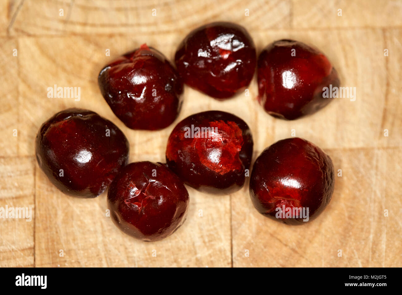 glace cherries on a wooden board for inclusion in a baking recipe Stock Photo