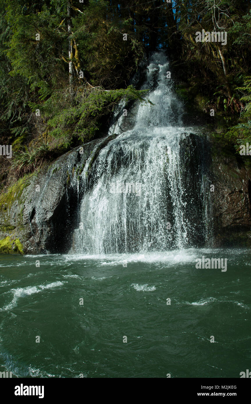 A stream cascades into Oregon's Siletz River photographed from a fishing boat. Stock Photo