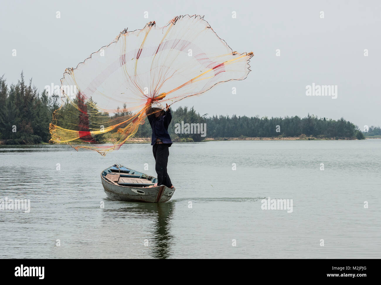 Vietnamese man casting a fishing net from a small boat on the river Thu Bon  in Hoi An everyday life Vietnam Asia Stock Photo - Alamy