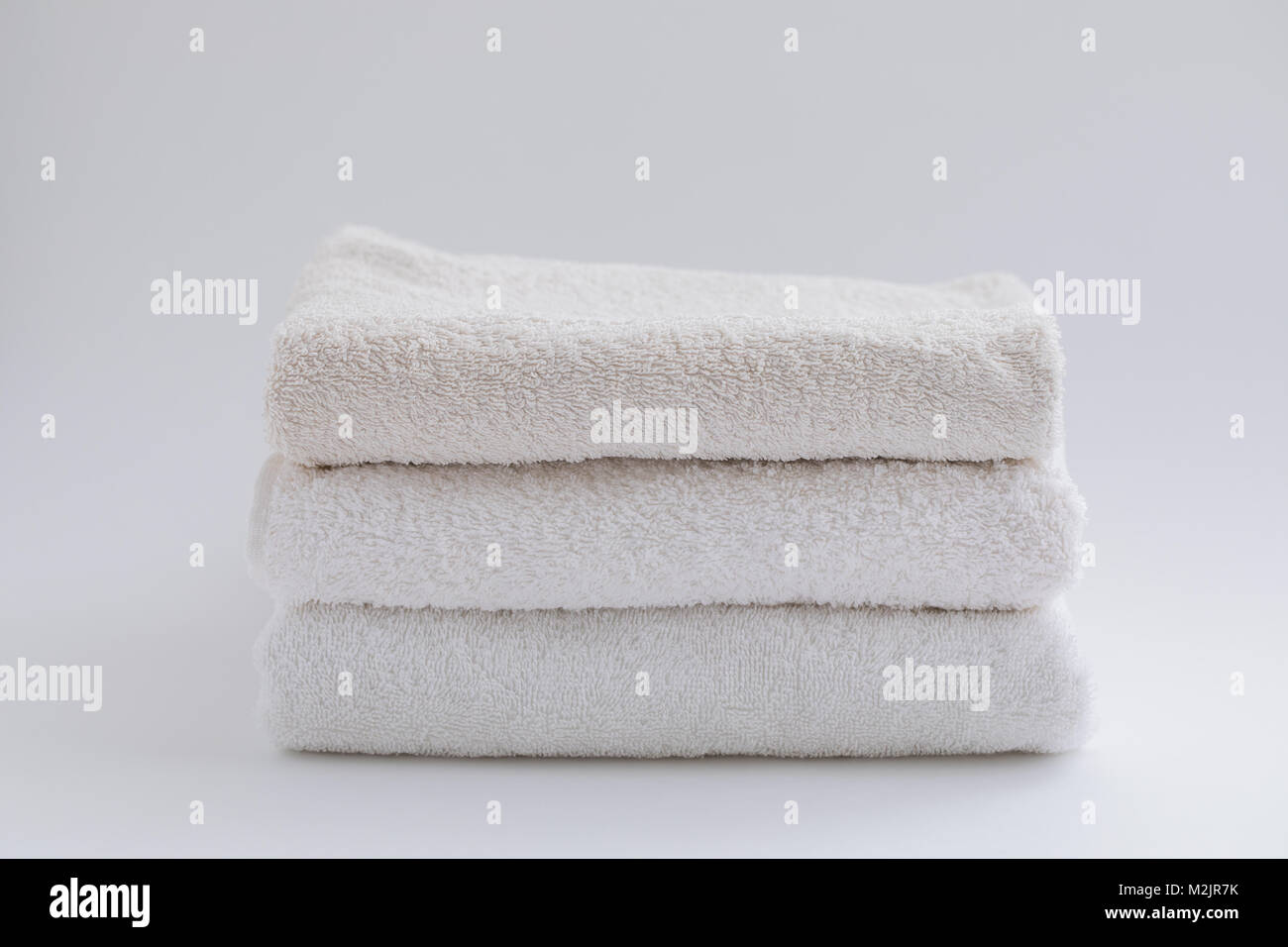 A pile of beige and white bath towels on a white background. Isolated