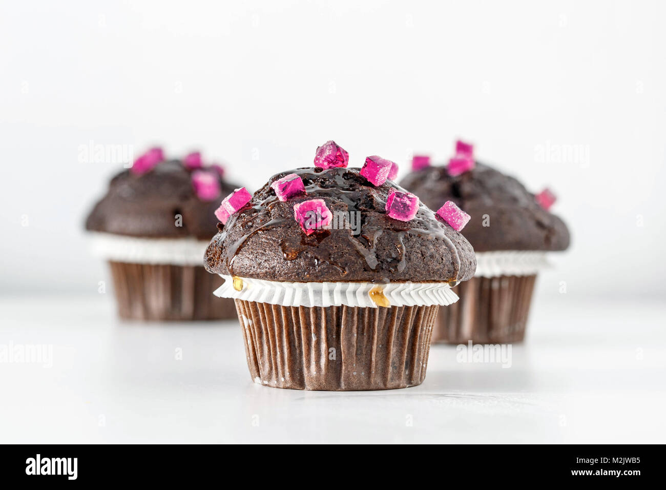 Baked Chocolate Muffins decorated with pink candies on white background ...