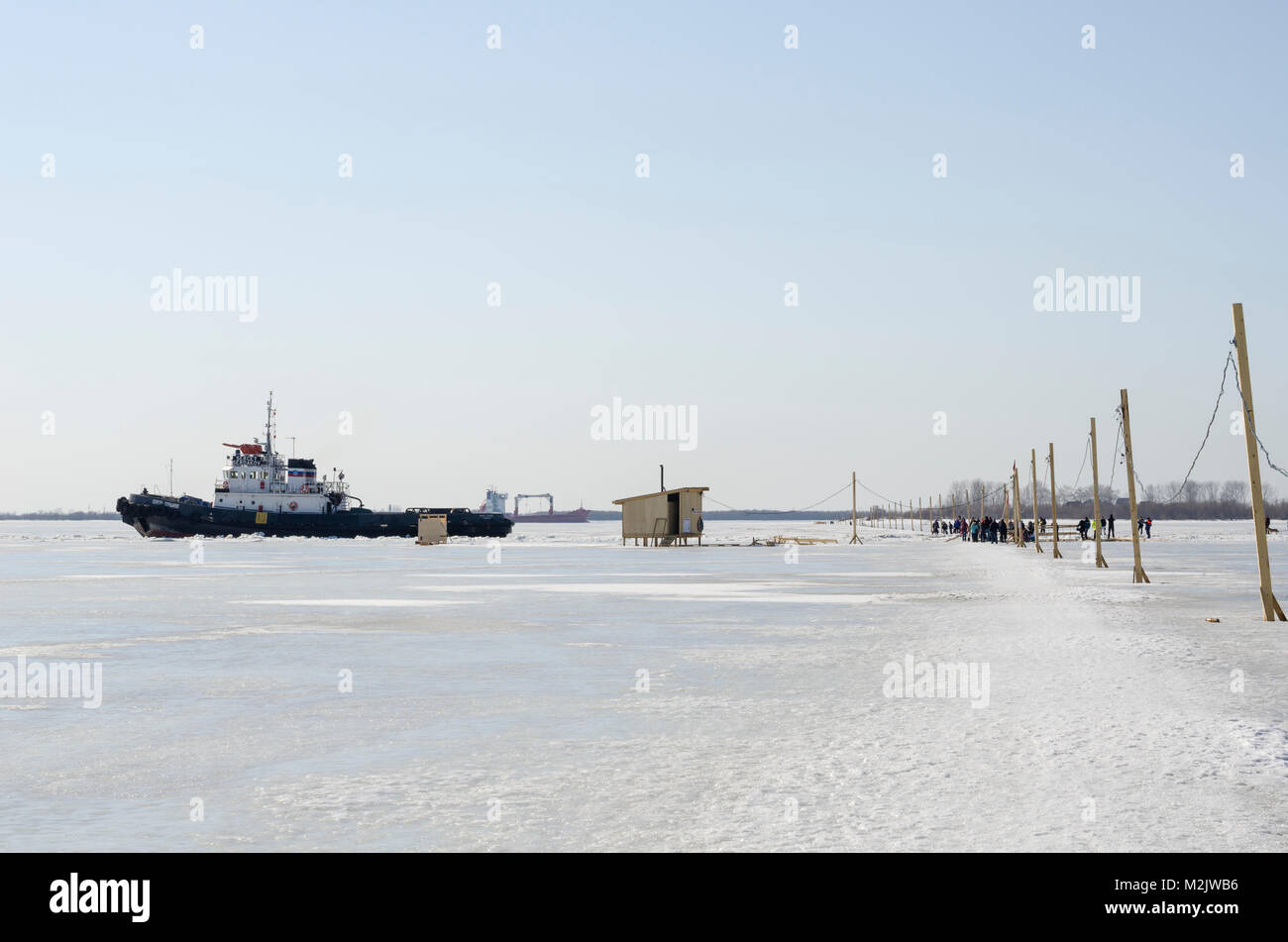 Icebreaker walking along the river past the pedestrian ice crossing