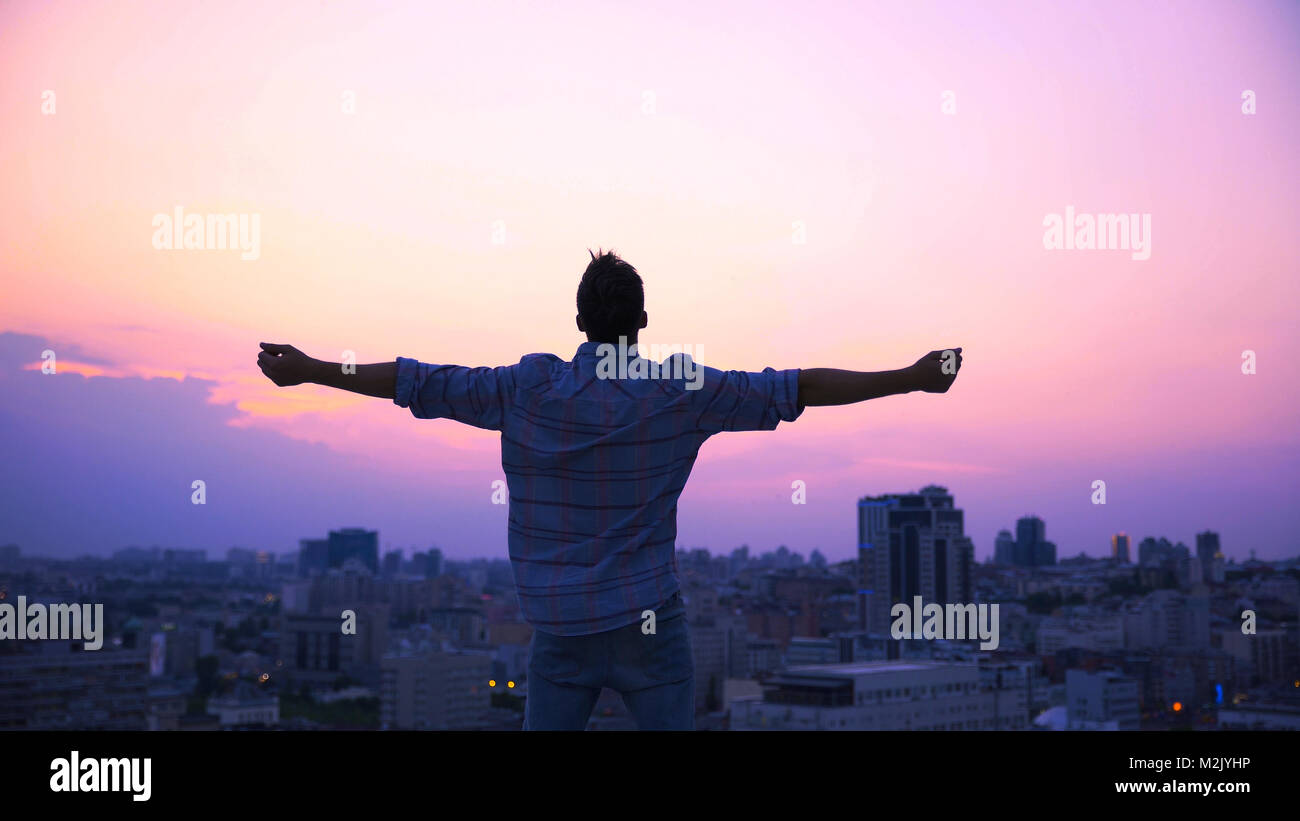 Man stretching hands on roof edge, enjoying freedom, believe in future success Stock Photo